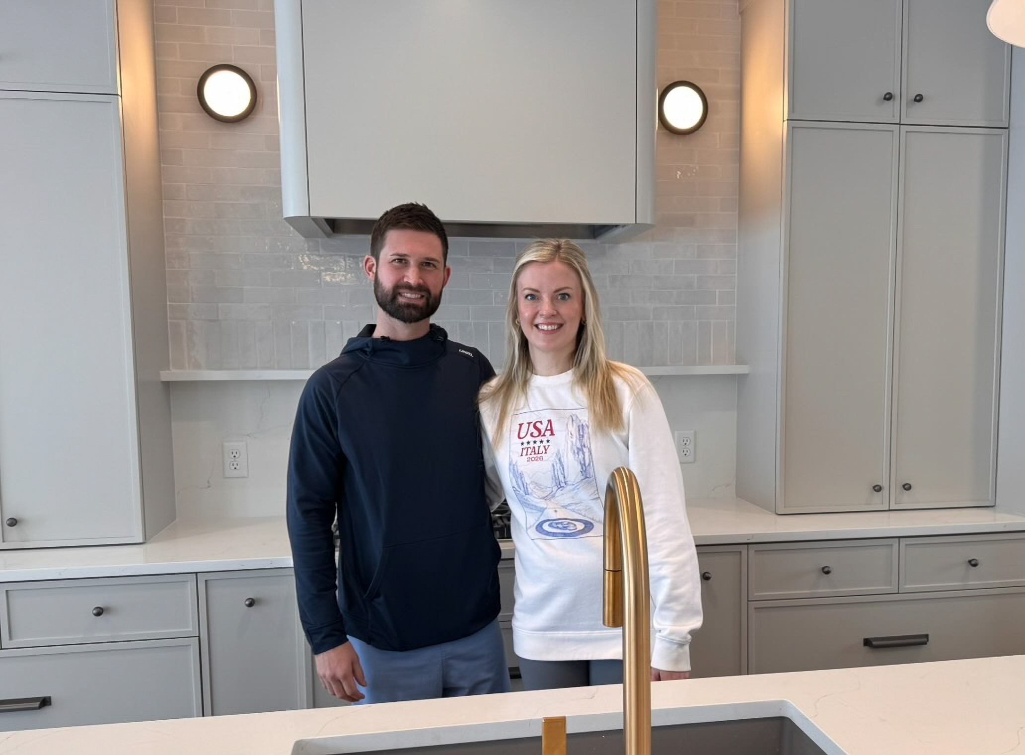 Happy homeowners in completed luxury kitchen with quartz countertops and designer finishes